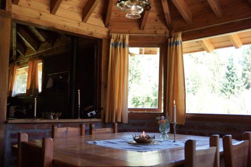 a dining room with a table and two windows at Estancia La Esperanza in San Carlos de Bariloche