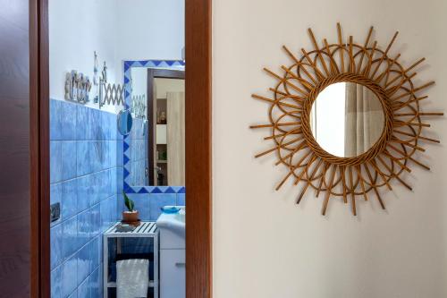 a bathroom with a mirror and a blue tiled wall at Domo Anghèleda - Alghero casa indipendente vicino al mare in Alghero