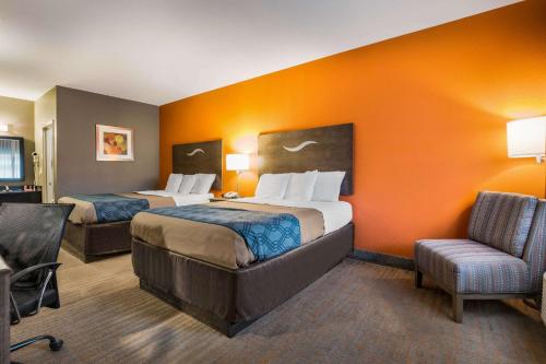 una habitación de hotel con 2 camas y una silla en Econo Lodge Forrest City I-40 en Forrest City