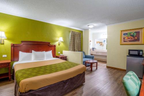 a hotel room with a bed and a chair at Rodeway Inn & Suites Fort Jackson in Columbia
