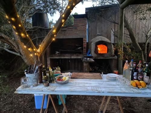an outdoor table with a pizza oven in a backyard at Rico Pino eco posada in La Pedrera