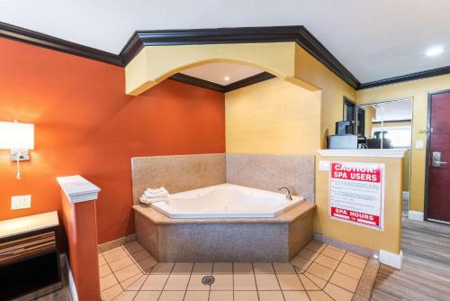Quality Inn & Suites في سكرامنتو: حوض استحمام في غرفة مع جدار برتقالي