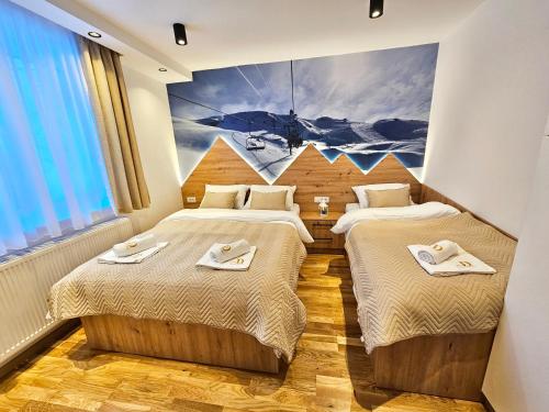 zwei Betten in einem Zimmer mit einem Gemälde an der Wand in der Unterkunft Dream Luxury Jahorina in Jahorina