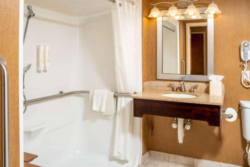 a bathroom with a tub and a sink and a mirror at Clarion Pointe Harrisonburg in Harrisonburg