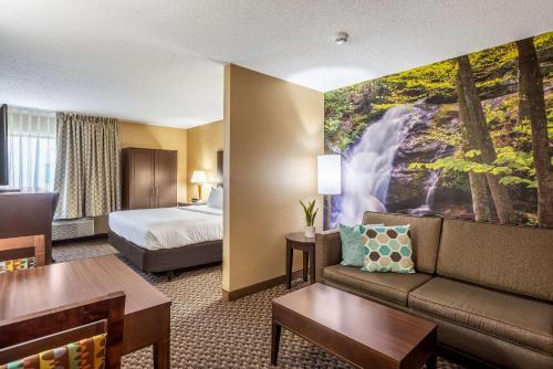 una camera d'albergo con divano, letto e murale a cascata di Clarion Pointe Harrisonburg a Harrisonburg