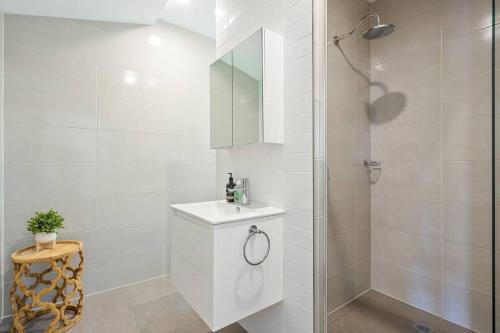 La salle de bains blanche est pourvue d'un lavabo et d'une douche. dans l'établissement Kiama Coastal Haven, à Kiama