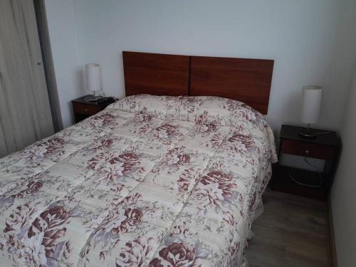 a bedroom with a bed with a floral bedspread at Lindo y acogedor departamento. in Concón