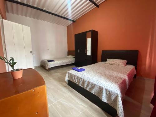 a bedroom with two beds in a room with orange walls at Habitación para 1-4 personas in Ibagué
