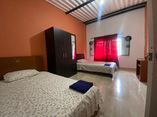 a bedroom with two beds and a window with red curtains at Habitación para 1-4 personas in Ibagué