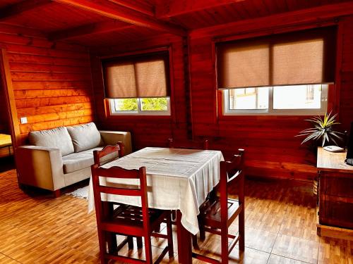 a dining room with a table and chairs and a couch at Vila Emigrante in Capelas