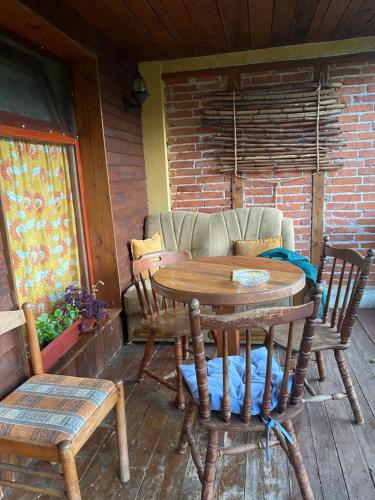 una mesa de madera y sillas en un porche con sofá en Farma 2 en Cazin