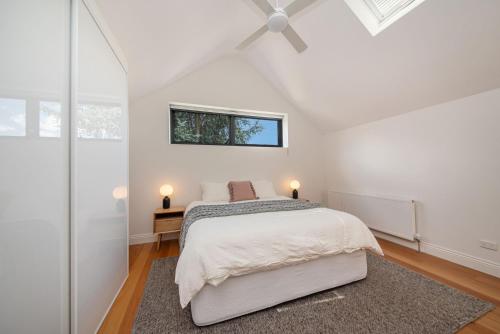 a white bedroom with a bed and a window at The Victorian Secret in Flemington in Melbourne