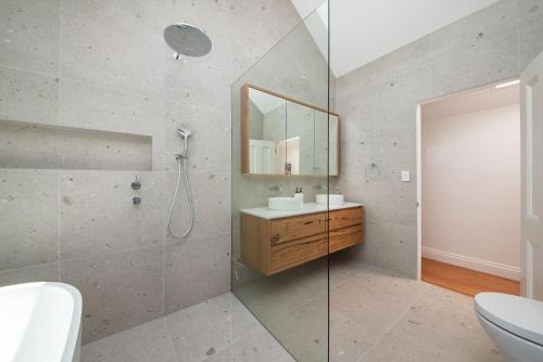 uma casa de banho com um chuveiro, um lavatório e um espelho. em The Victorian Secret in Flemington em Melbourne