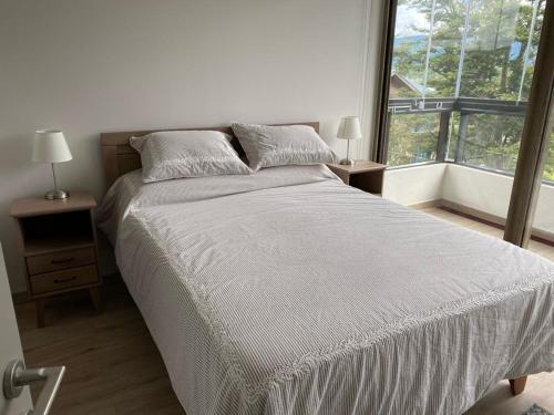 Un dormitorio con una cama grande y una ventana en Acogedor y céntrico departamento en Pucón en Pucón