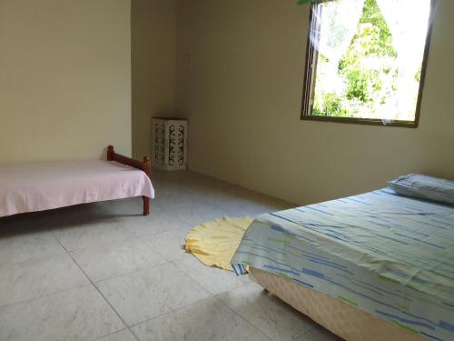 a bedroom with two beds and a window and a rug at Suítes Recanto Dos Passarinhos 2 in Ubatuba