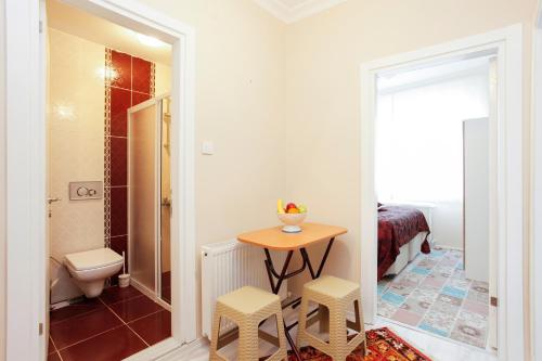 ein Badezimmer mit einem WC und einem Tisch mit zwei Stühlen in der Unterkunft Blue Sultan Apart in Istanbul