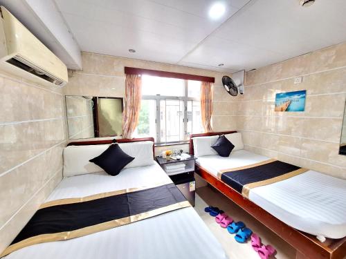 two beds in a small room with a window at International Metro Guest House in Hong Kong