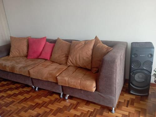 a brown couch with two pink pillows and a speaker at Habitación acogedora in Quito