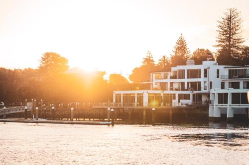 a building next to the water with the sun setting at Trinity Wharf Tauranga in Tauranga