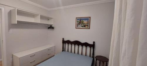 a small white bedroom with a bed and a cabinet at Ap 154 Balneário Piçarras in Piçarras