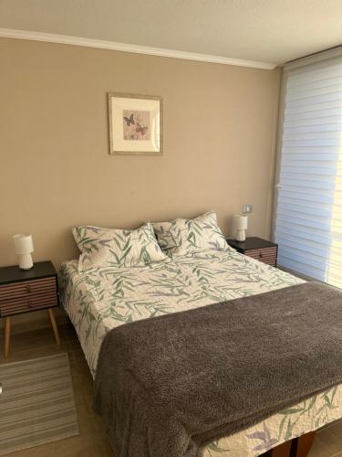 a bedroom with a bed with two nightstands and two lamps at Departamento Viña del Mar in Viña del Mar