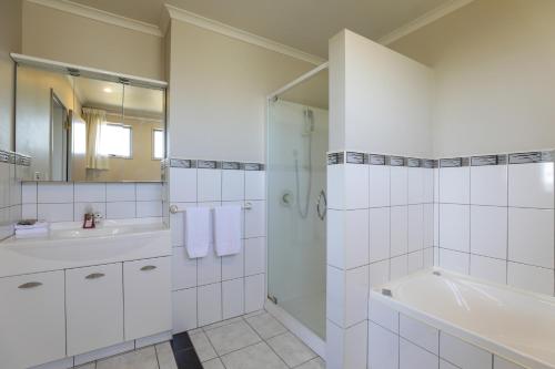 La salle de bains blanche est pourvue d'une douche, d'une baignoire et d'un lavabo. dans l'établissement Top of the Lake - Taupo, à Taupo