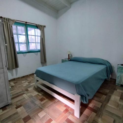 een slaapkamer met een bed met een blauwe deken bij Níspero in San Marcos Sierras