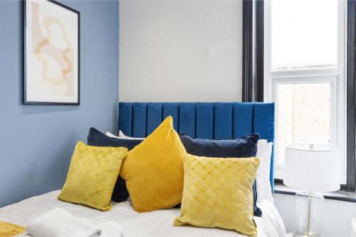 a bedroom with a bed with yellow pillows at Amber and Blue: Newly Renovated Designer Flat in London