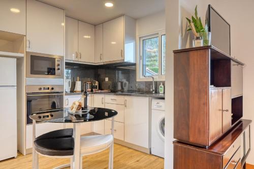 a kitchen with white cabinets and a glass table at Casa Familia Pestana 2, a Home in Madeira in Seixal