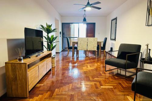 een woonkamer met een televisie en een tafel met stoelen bij Confortable & estiloso departamento en la ciudad de Mendoza in Mendoza