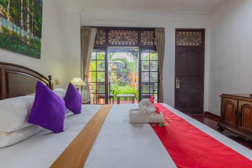 sypialnia z dużym łóżkiem i czerwonym kocem w obiekcie Puri Mango Guest House Sanur w mieście Sanur