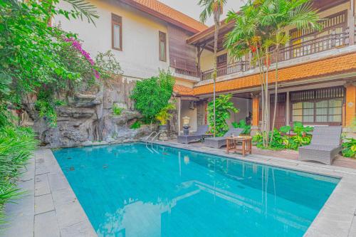 a swimming pool in front of a house at Puri Mango Guest House Sanur in Sanur