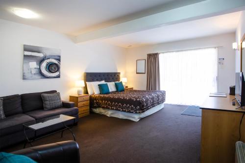 a living room with a bed and a couch at Casino Court Motor Lodge in Christchurch