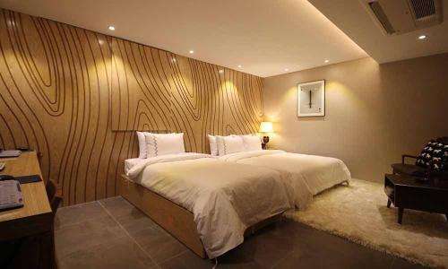 a bedroom with a large bed with a wooden wall at Jeonju Mari Hotel in Jeonju
