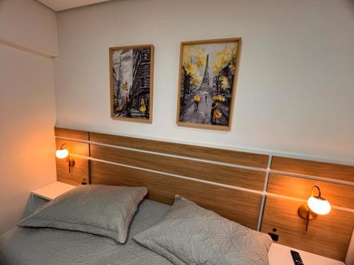 舊巴拉的住宿－Resort Pé na Areia próximo Beto Carrero，卧室配有一张床,墙上挂有两张照片
