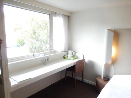 a bedroom with a window with a desk and a chair at Campanile Biarritz in Biarritz