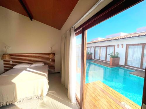 a bedroom with a bed and a swimming pool at Vila Mandakaru in São Miguel do Gostoso