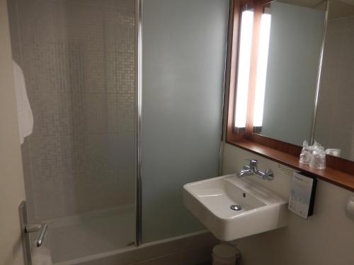 a bathroom with a shower and a sink and a mirror at Campanile Biarritz in Biarritz