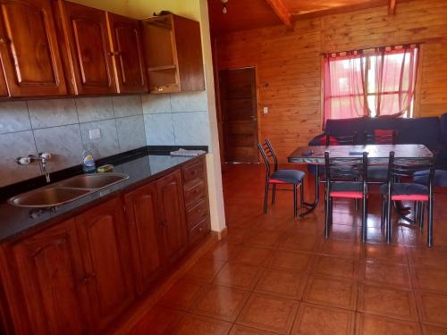 a kitchen with a sink and a table with chairs at LA CABAÑA DE SERGIO in Gobernador Roca