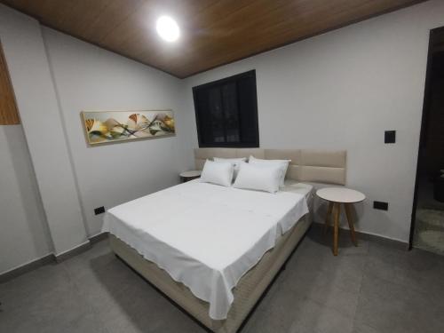 a bedroom with a white bed and a table at Villa São Lourenço in Bertioga