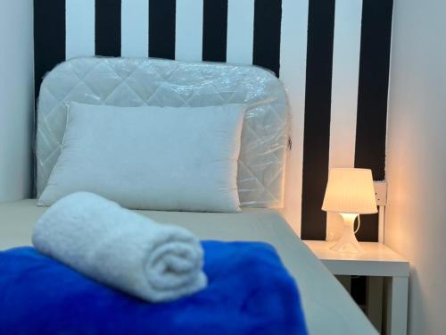 a bed with a blue blanket and a white pillow at Striped Partition Room in Barsha 1 Near Mall of the Emirates in Dubai