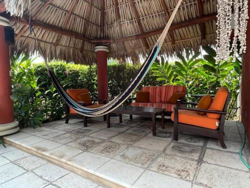 a hammock and chairs on a patio under a straw umbrella at Casa Gaviota in San José de Guatemala