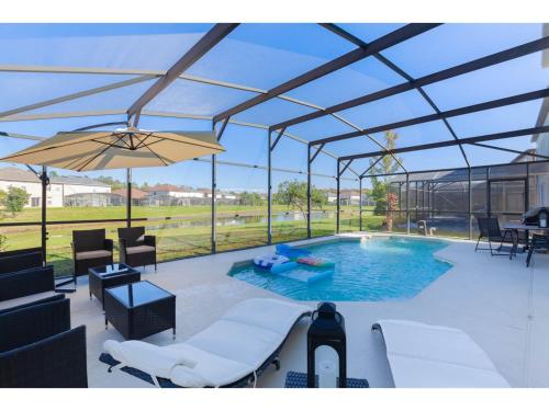 a pavilion with a pool and chairs and an umbrella at Best place to unwind and have lots of fun! in Kissimmee