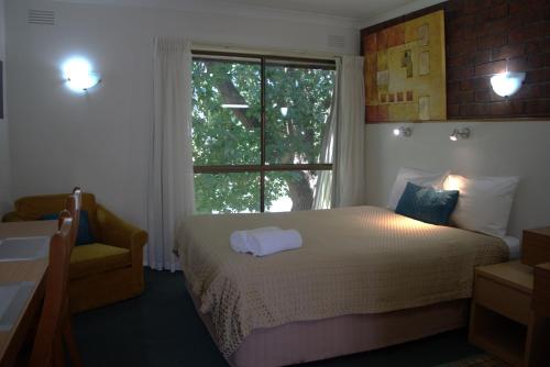 a bedroom with a bed and a large window at City Gardens Motel in Traralgon