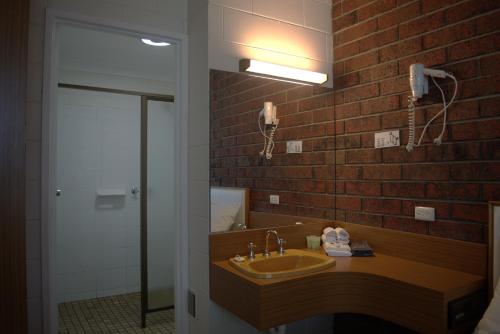 uma casa de banho com um lavatório e uma parede de tijolos em City Gardens Motel em Traralgon