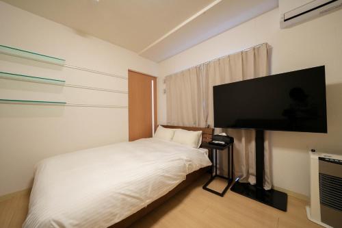 a bedroom with a bed and a flat screen tv at Residence Hotel Liberte in Sapporo