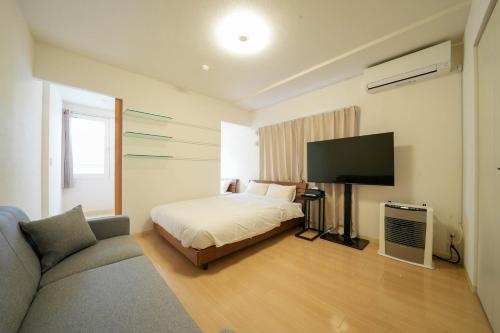 a bedroom with a bed and a flat screen tv at Residence Hotel Liberte in Sapporo