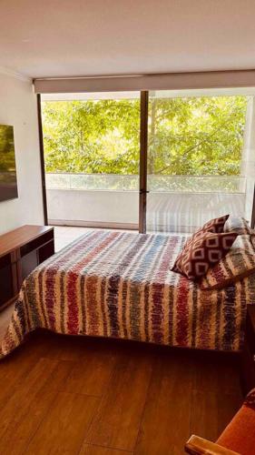 1 dormitorio con cama y ventana grande en Apartamento en Las Condes frente a parque araucano, en Santiago