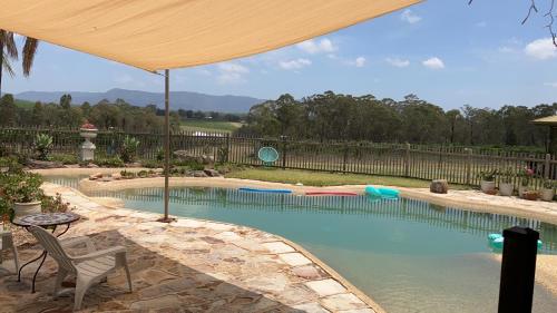 einen Pool mit Sonnenschirm, Tisch und Stühlen in der Unterkunft Blueberry Hill Vineyard Stay in Rothbury