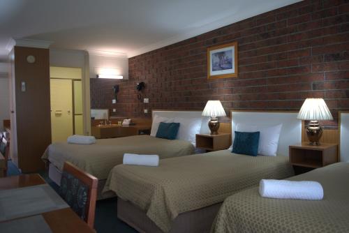 pokój hotelowy z 2 łóżkami i ceglaną ścianą w obiekcie City Gardens Motel w mieście Traralgon